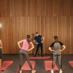 People stretching on yoga mats during a fitness class indoors.
